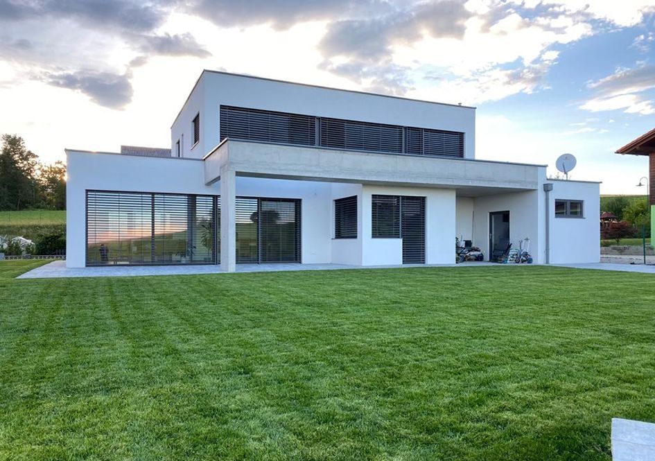 Modernes Flachdachhaus mit großer Glasfront und gepflegtem Rasen