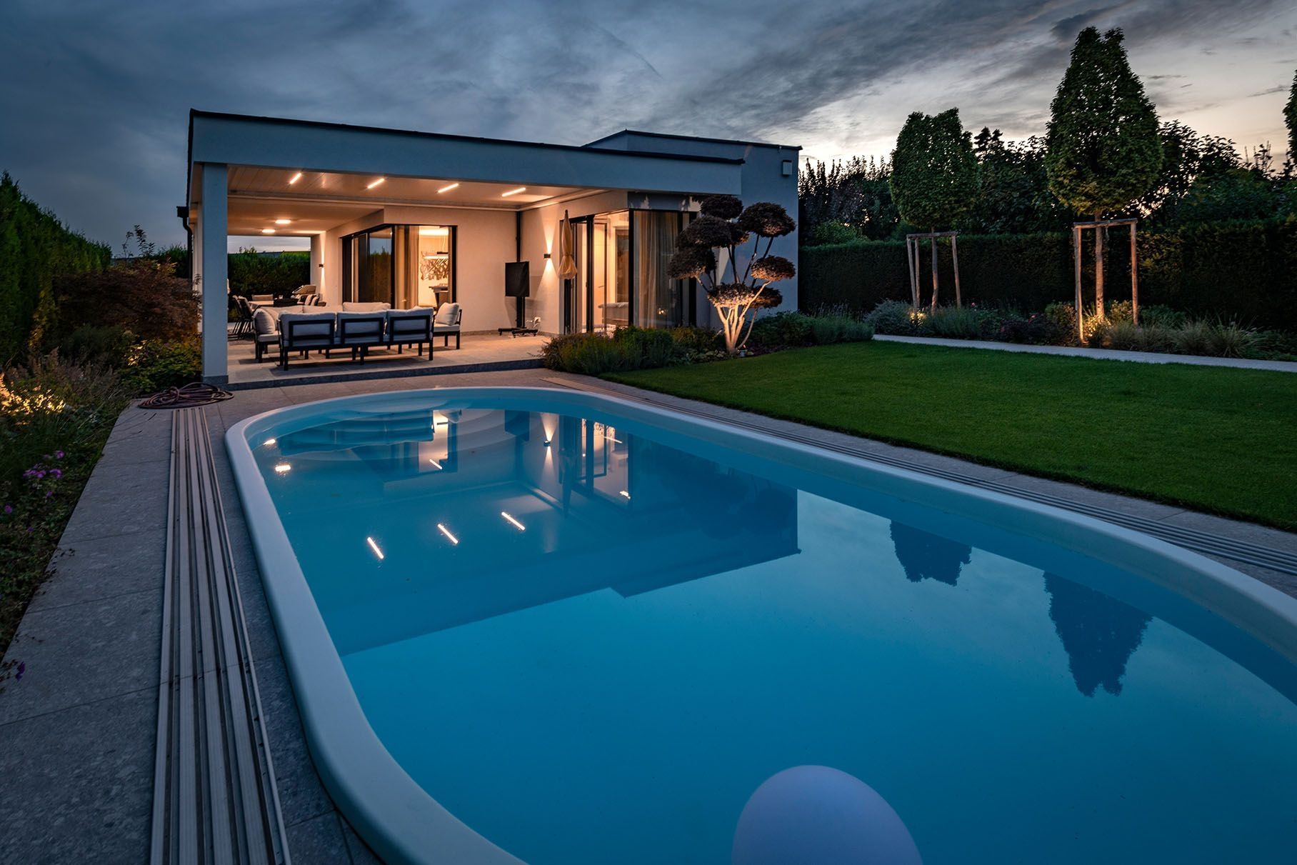 Moderner Bungalow mit Pool und beleuchteter Terrasse am Abend