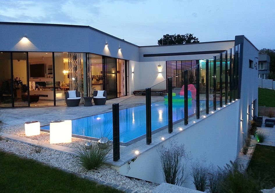 Moderne Villa mit Pool und Glasgeländer am Abend