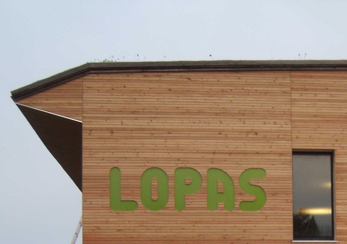 Holzfassade mit grünem LOPAS Schriftzug