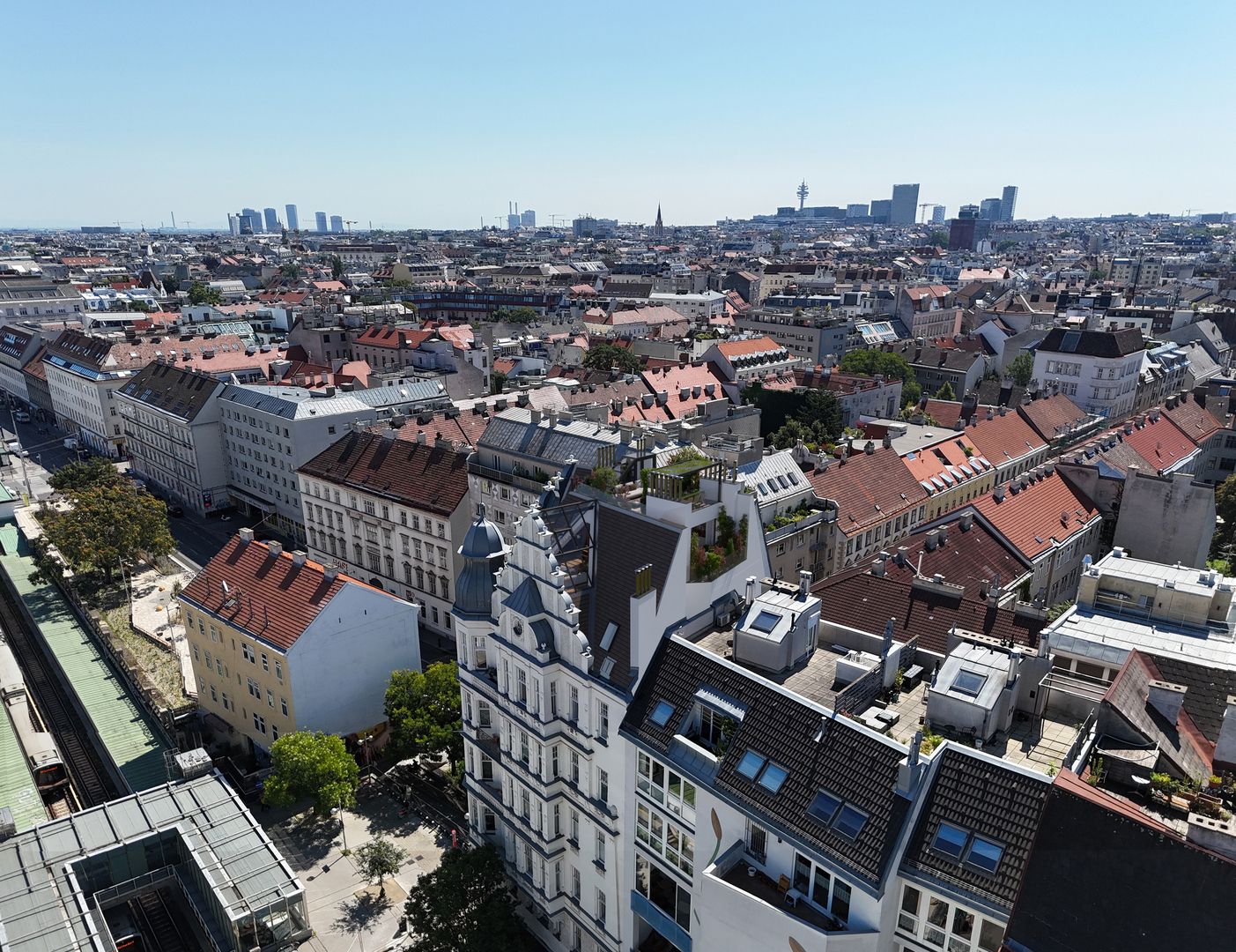 Luftaufnahme von dicht bebauten Wohngebäuden mit roten Dächern und moderner Skyline im Hintergrund in Wien