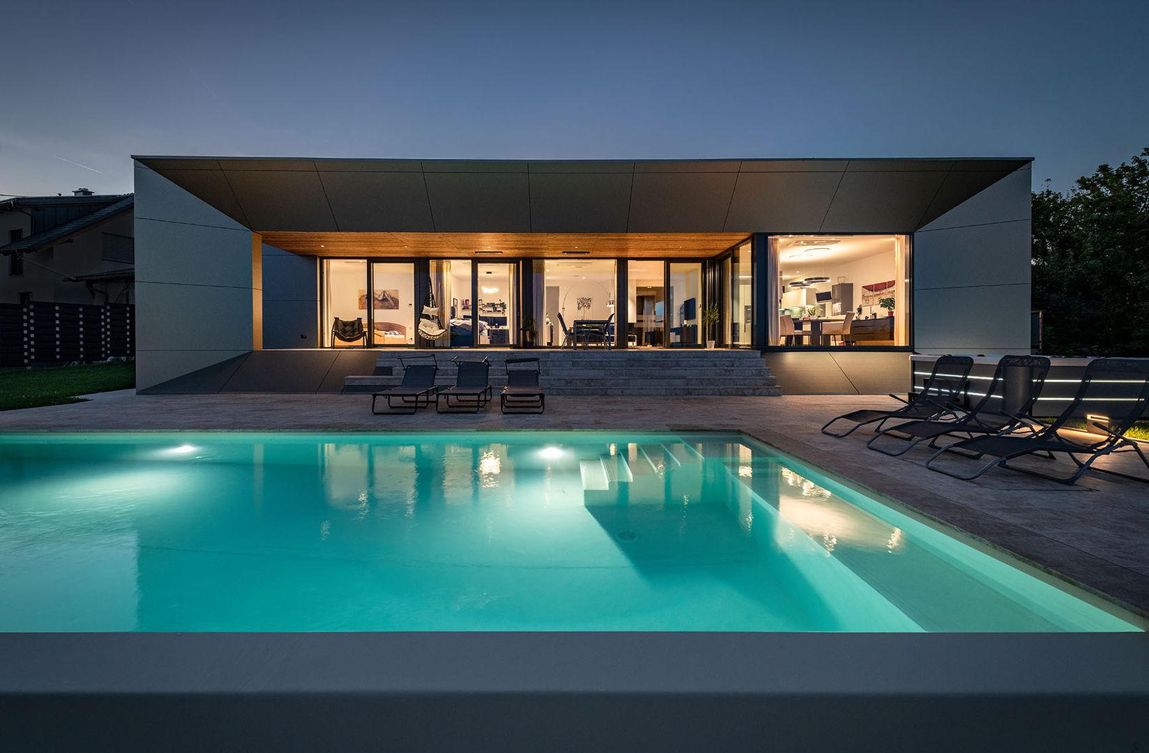 Moderner Bungalow mit Pool und Glasfassade bei Nacht